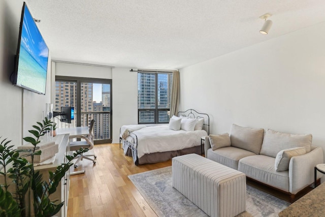 bedroom with a textured ceiling, wood finished floors, and access to exterior