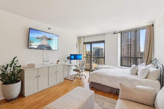 bedroom featuring access to exterior, a textured ceiling, and light wood-style floors