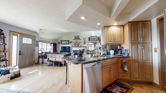 kitchen with kitchen peninsula, dark stone countertops, sink, a kitchen bar, and stainless steel dishwasher