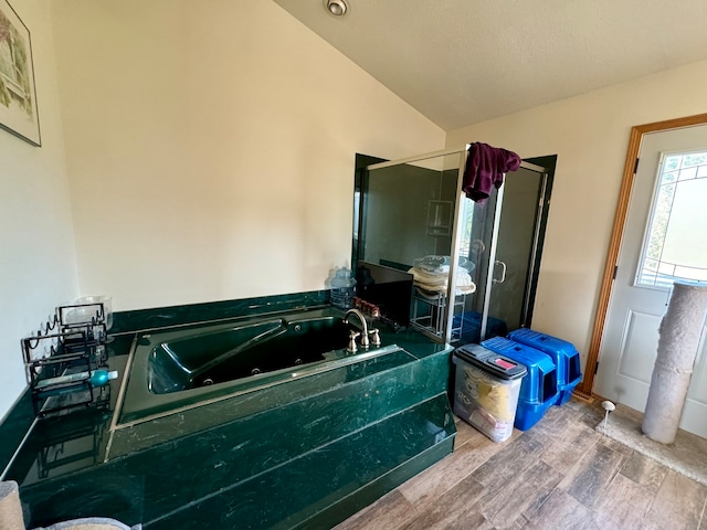 bathroom with a textured ceiling, vaulted ceiling, plus walk in shower, and wood-type flooring