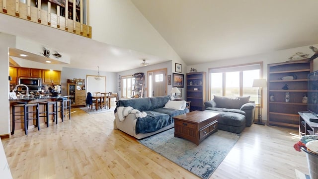 living room featuring high vaulted ceiling and light wood-type flooring