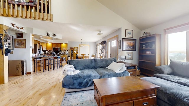 living room featuring a wealth of natural light, high vaulted ceiling, and light wood-type flooring