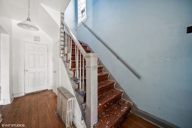 stairway with hardwood / wood-style flooring and radiator heating unit