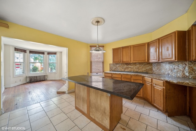 kitchen with light hardwood / wood-style flooring, tasteful backsplash, radiator, decorative light fixtures, and a center island