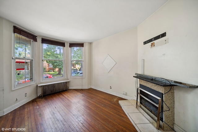 unfurnished living room featuring hardwood / wood-style flooring, radiator heating unit, and a fireplace