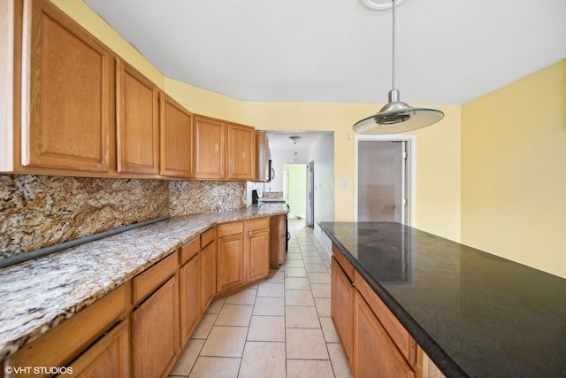 kitchen featuring light tile patterned floors, backsplash, pendant lighting, and light stone countertops