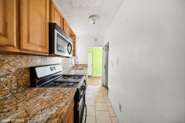 kitchen featuring appliances with stainless steel finishes, decorative backsplash, sink, light stone countertops, and light tile patterned flooring