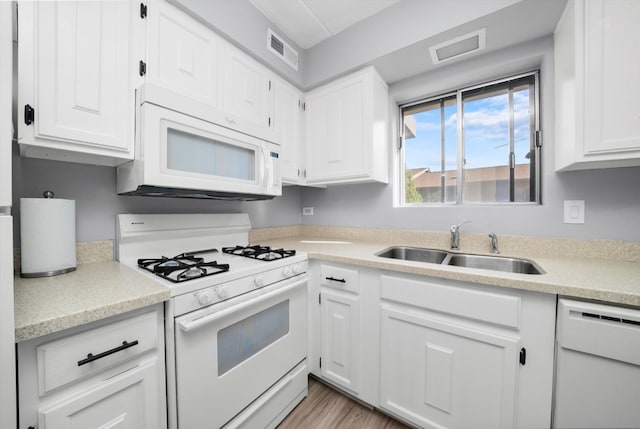 kitchen featuring white appliances, sink, light wood-type flooring, and white cabinets