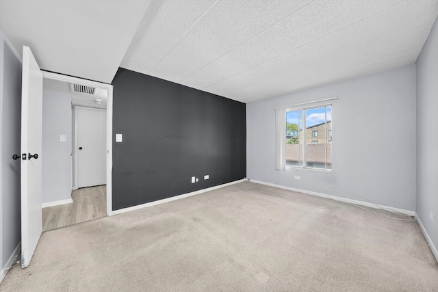 carpeted empty room featuring a textured ceiling