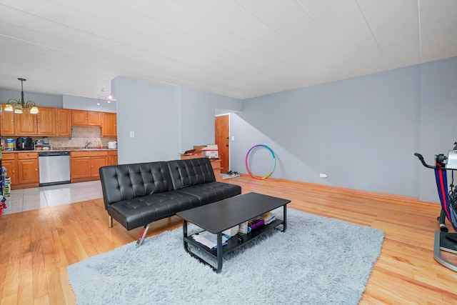 living room with light hardwood / wood-style floors, sink, and an inviting chandelier