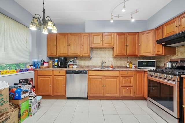 kitchen featuring appliances with stainless steel finishes, decorative light fixtures, rail lighting, extractor fan, and a notable chandelier