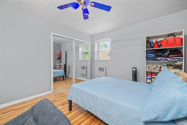 bedroom featuring ceiling fan, light wood-type flooring, a closet, and radiator