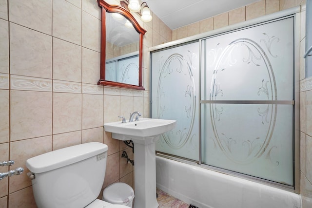 full bathroom featuring tile walls, enclosed tub / shower combo, sink, and toilet