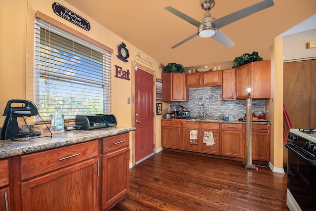 kitchen featuring white range with gas stovetop, tasteful backsplash, dark wood-type flooring, and sink