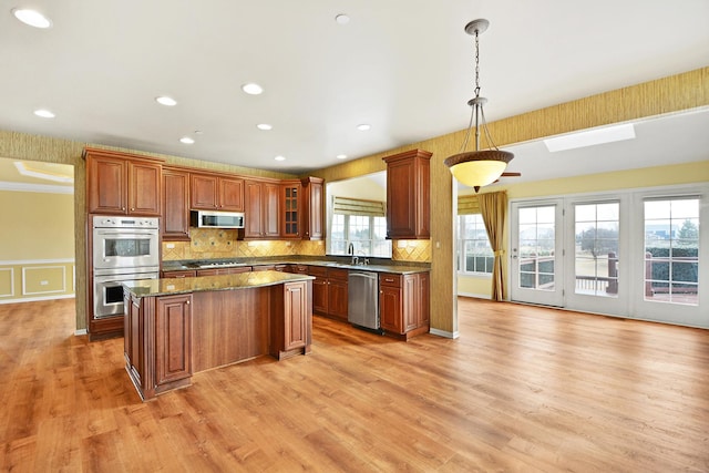 kitchen with sink, hanging light fixtures, a center island, light hardwood / wood-style floors, and stainless steel appliances