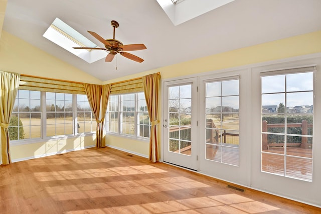 unfurnished sunroom featuring lofted ceiling with skylight, a healthy amount of sunlight, and ceiling fan