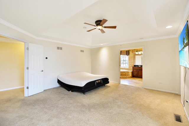 carpeted bedroom with ceiling fan, ornamental molding, a tray ceiling, and ensuite bathroom