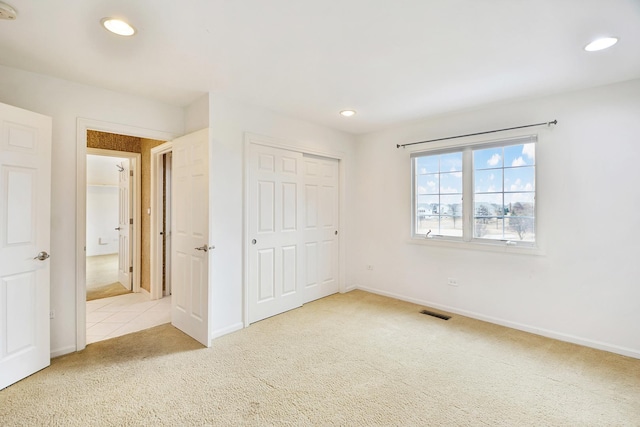 unfurnished bedroom with a closet and light carpet