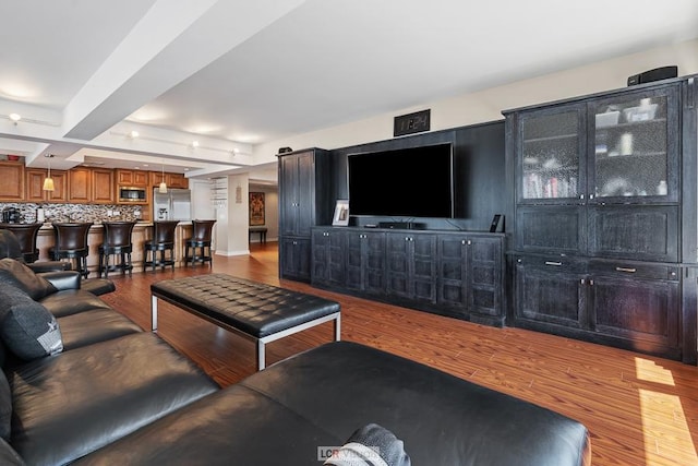 living area with beam ceiling and wood finished floors