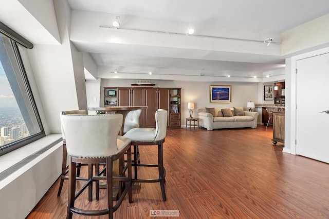 dining area with a dry bar, rail lighting, and dark wood-style flooring