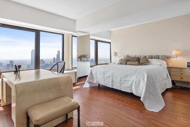 bedroom with a view of city and dark wood-type flooring