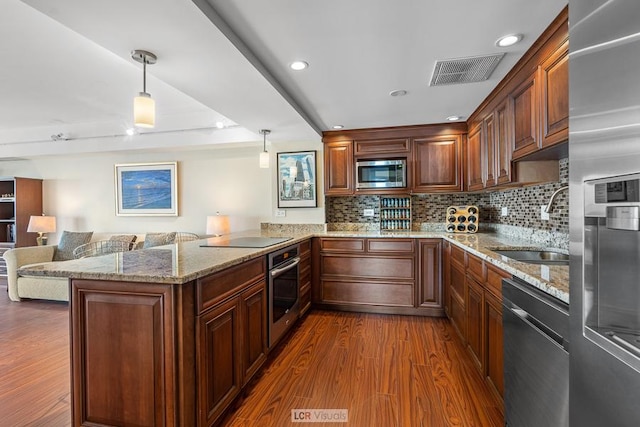 kitchen featuring visible vents, dark wood-type flooring, appliances with stainless steel finishes, a peninsula, and a sink