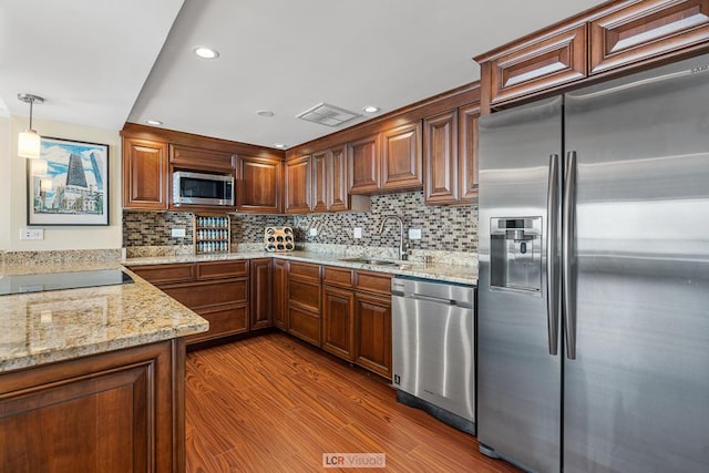 kitchen featuring a sink, backsplash, appliances with stainless steel finishes, light stone countertops, and dark wood-style flooring