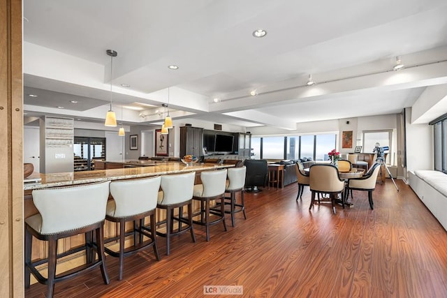 kitchen with open floor plan, a breakfast bar, dark wood-type flooring, and light stone countertops