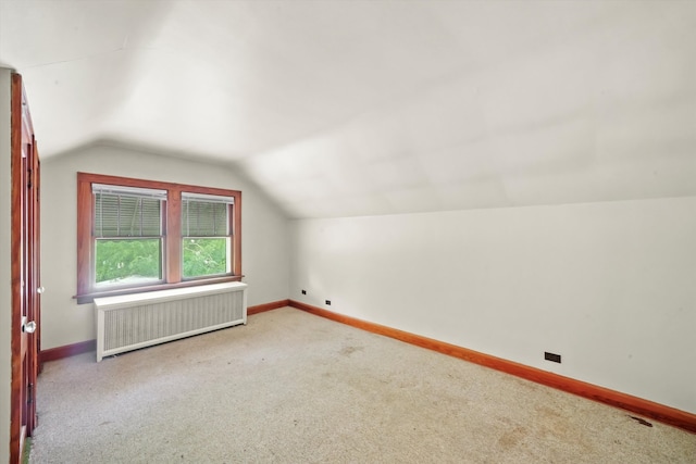 additional living space featuring radiator heating unit, lofted ceiling, and carpet flooring