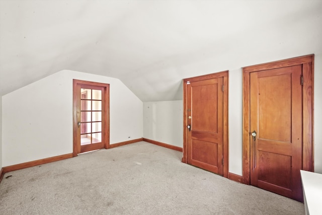 additional living space featuring light colored carpet and vaulted ceiling