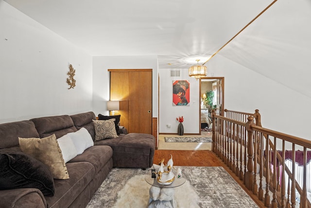 living area featuring a chandelier, visible vents, baseboards, and lofted ceiling