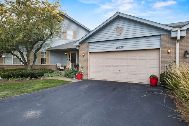 traditional-style home with brick siding, aphalt driveway, and a garage