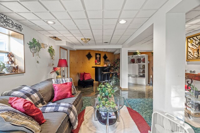 tiled living room featuring recessed lighting, a paneled ceiling, and wood walls