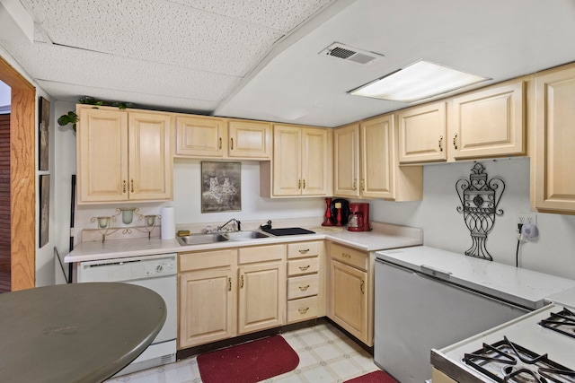 kitchen featuring light brown cabinetry, dishwashing machine, visible vents, and a sink