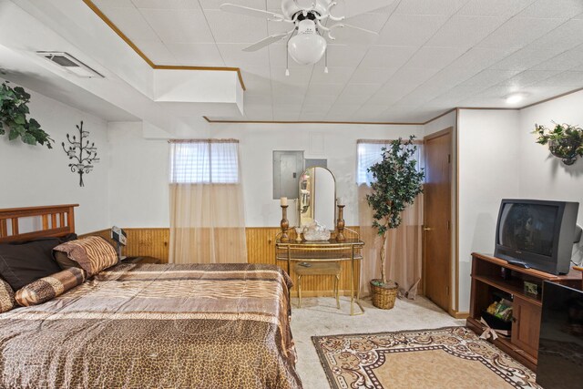 carpeted bedroom featuring visible vents, ceiling fan, wooden walls, and a wainscoted wall