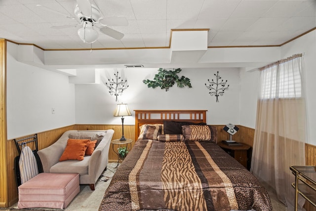 bedroom with a wainscoted wall, carpet floors, wooden walls, and ornamental molding