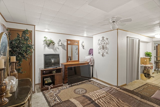 living area featuring baseboards, crown molding, a ceiling fan, and carpet floors