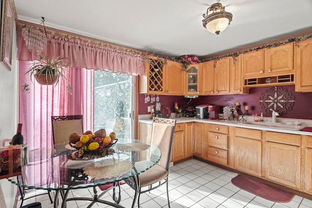 kitchen with light countertops, light tile patterned floors, glass insert cabinets, and a sink