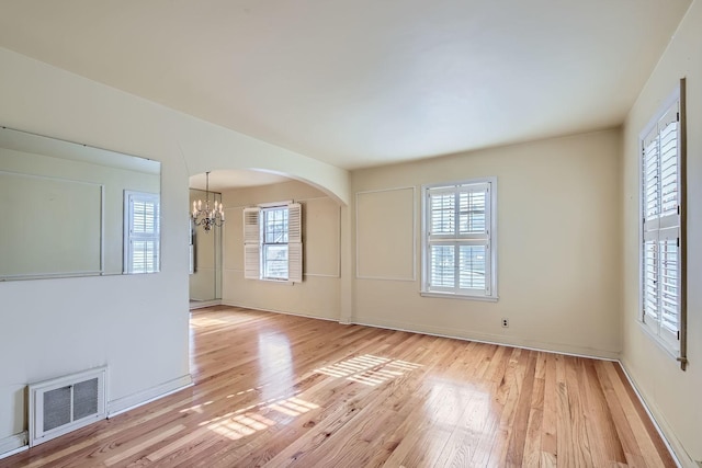 unfurnished room featuring a notable chandelier and light hardwood / wood-style floors