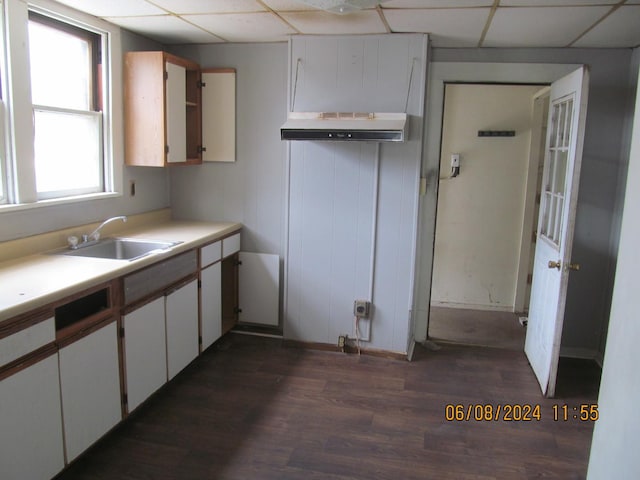 kitchen with dark wood finished floors, light countertops, white cabinets, a sink, and a drop ceiling