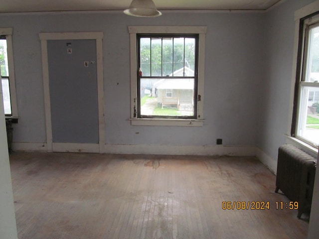 unfurnished room with a healthy amount of sunlight, radiator heating unit, baseboards, and light wood-style flooring