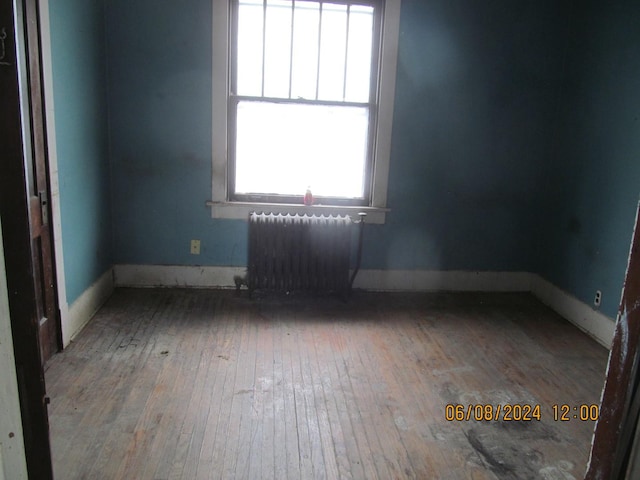 spare room featuring radiator, baseboards, and hardwood / wood-style floors