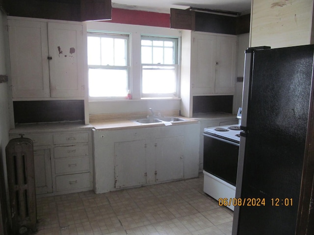 kitchen with white electric stove, a sink, white cabinetry, light countertops, and freestanding refrigerator