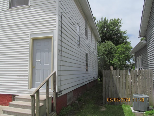 view of property exterior featuring entry steps, central AC unit, and fence