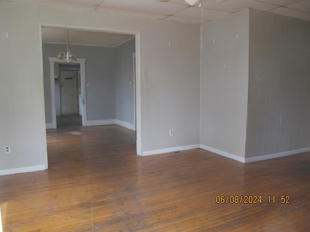 unfurnished room with a paneled ceiling, baseboards, and wood finished floors