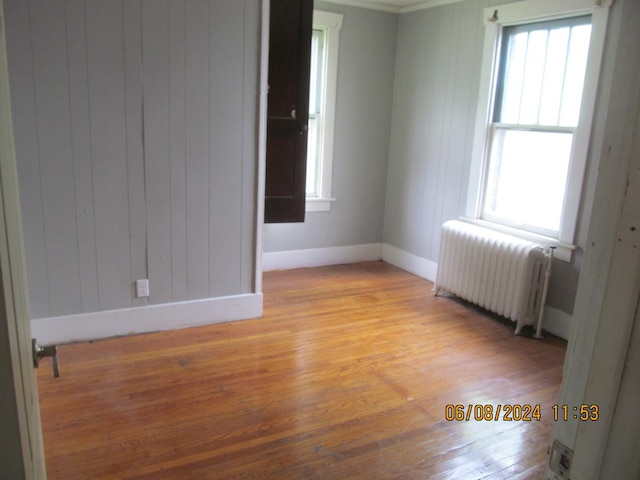 unfurnished room with light wood-style floors, radiator, and baseboards