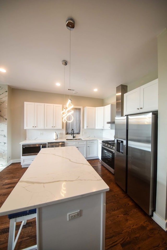 kitchen featuring dark hardwood / wood-style floors, white cabinetry, appliances with stainless steel finishes, decorative light fixtures, and a center island