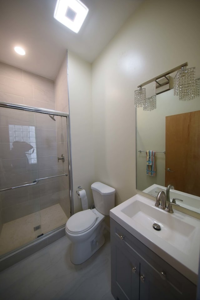 bathroom featuring toilet, vanity, and a shower with shower door