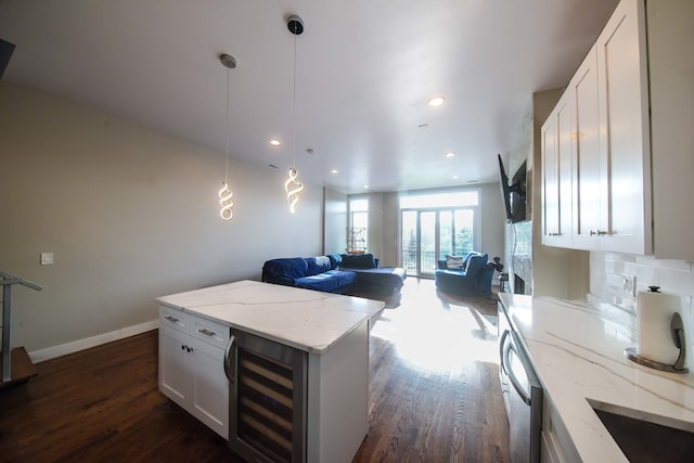 kitchen featuring dark wood-type flooring, tasteful backsplash, beverage cooler, white cabinets, and light stone counters