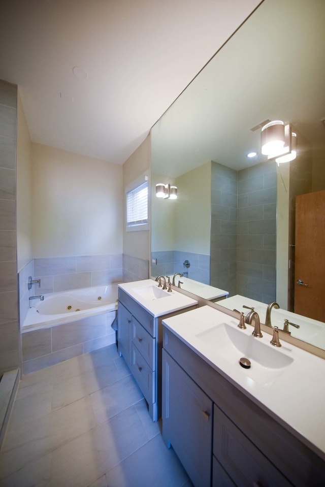 bathroom with tile patterned flooring, tiled tub, and vanity